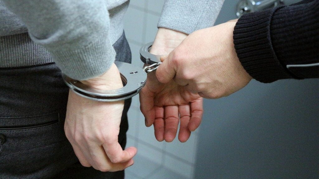 a pair of hands is locking another pair of hands into handcuffs