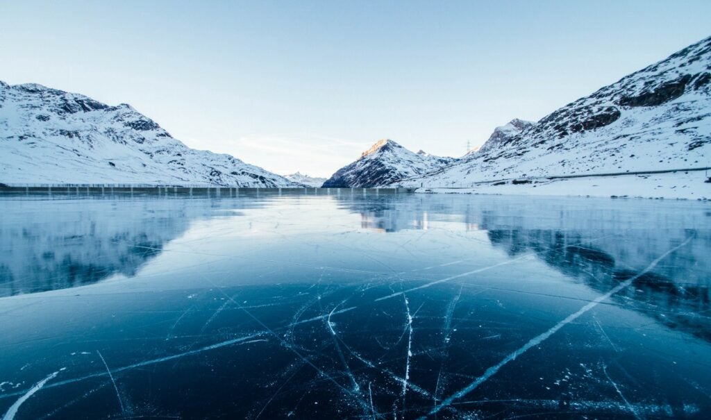 ice cracking in a body of water surrounded by snowy mountains