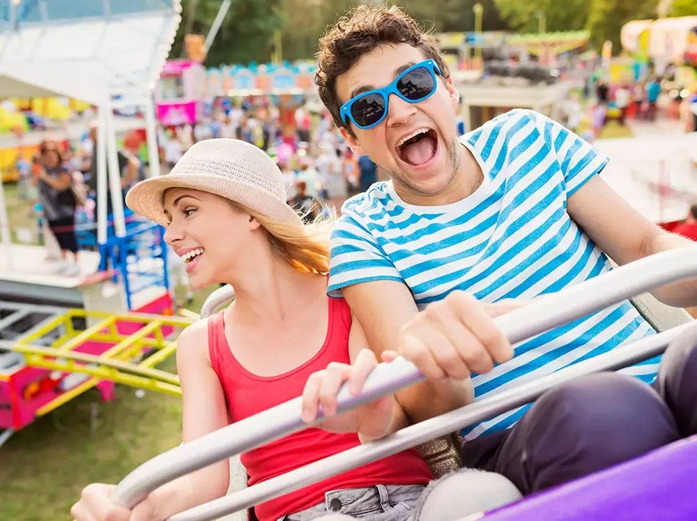 couple at fun fair riding roller coaster