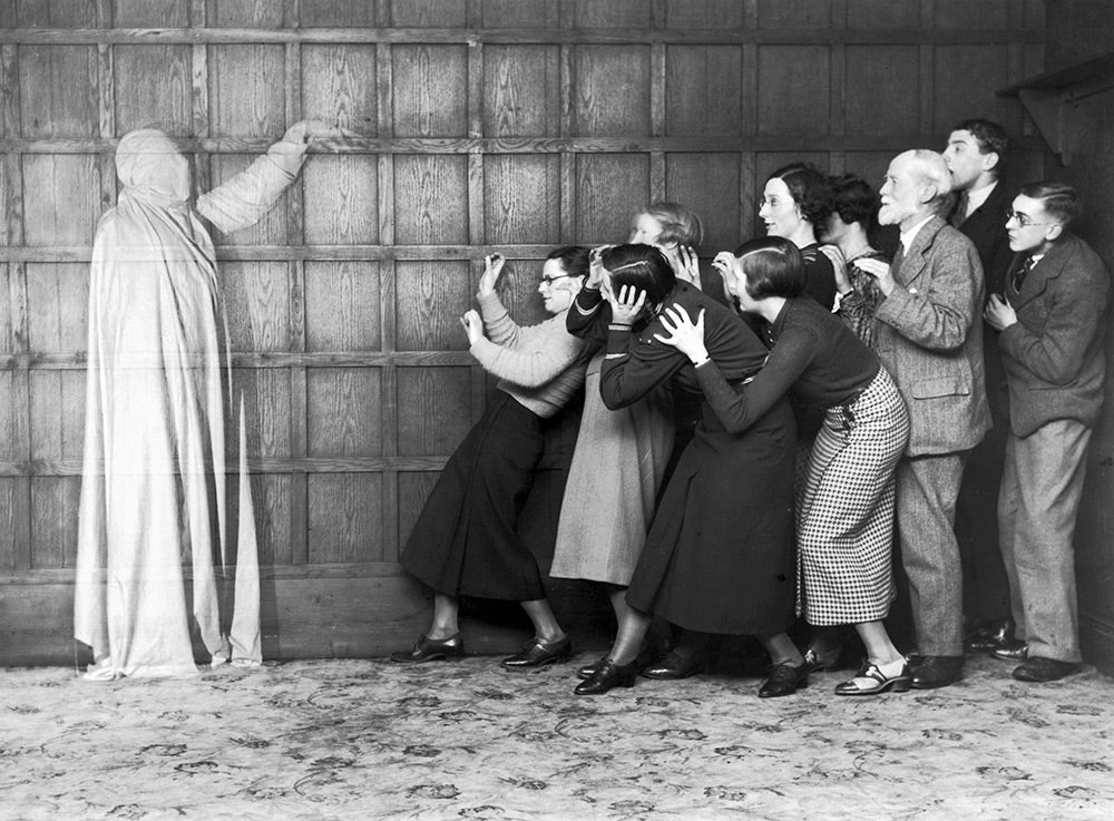 People cowering in fear at the sight of a ghost, c 1920s.
