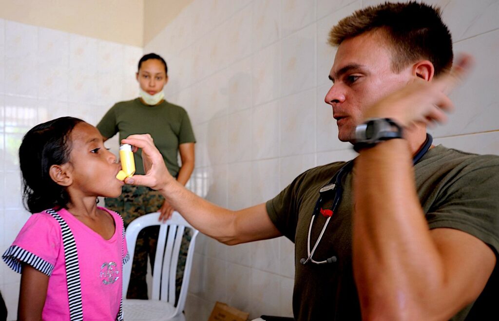 an adult shows a child how to use an inhaler