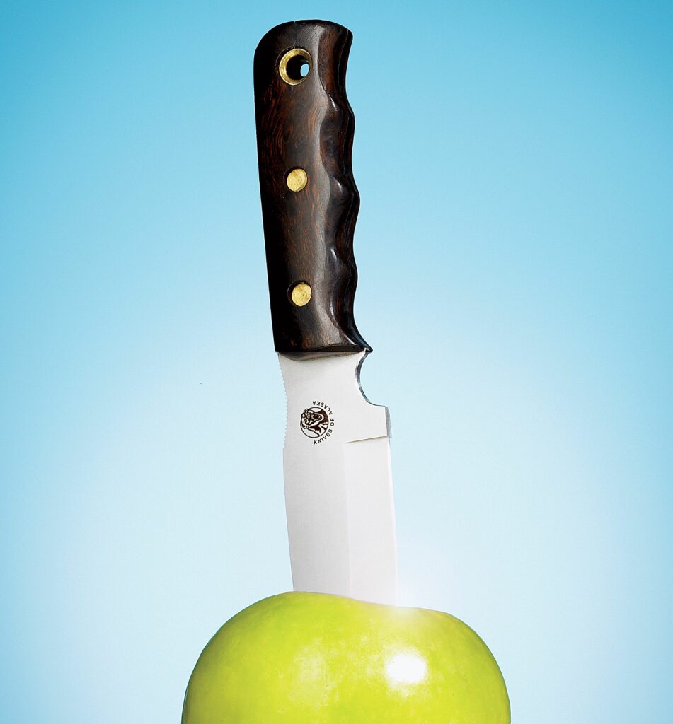 A sharp knife sticking out of an apple.