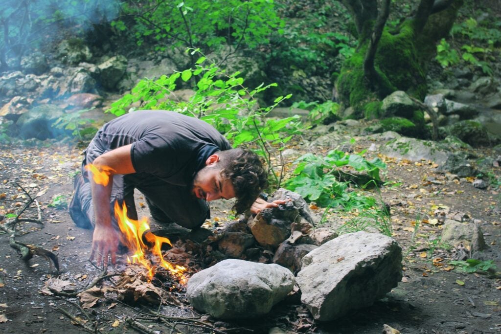 man lighting a fire in the outdoors