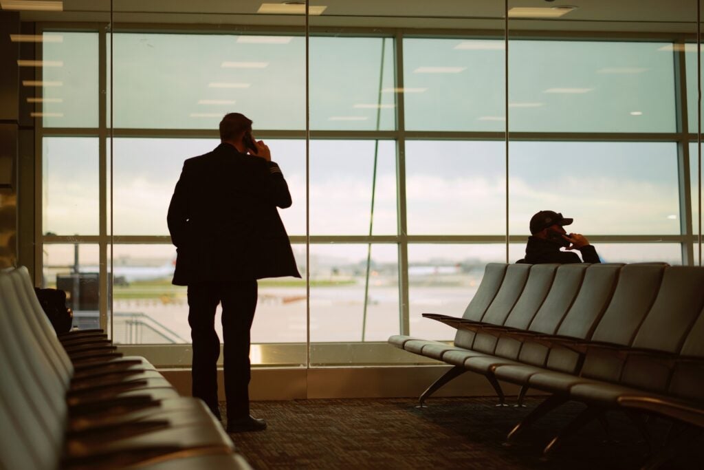 two people in an airport talking on phones