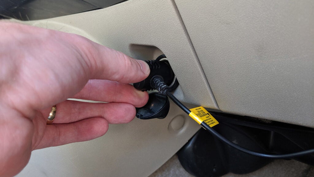 hand plugging a cable to a car cigarette lighter