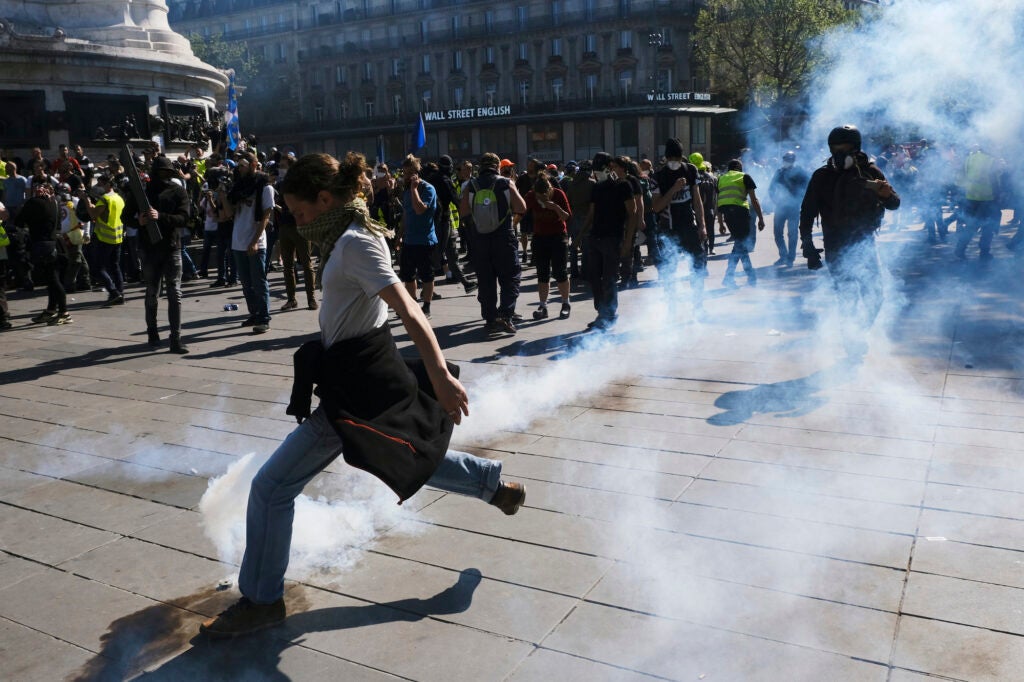 Person kicking teargas canister in Paris protests