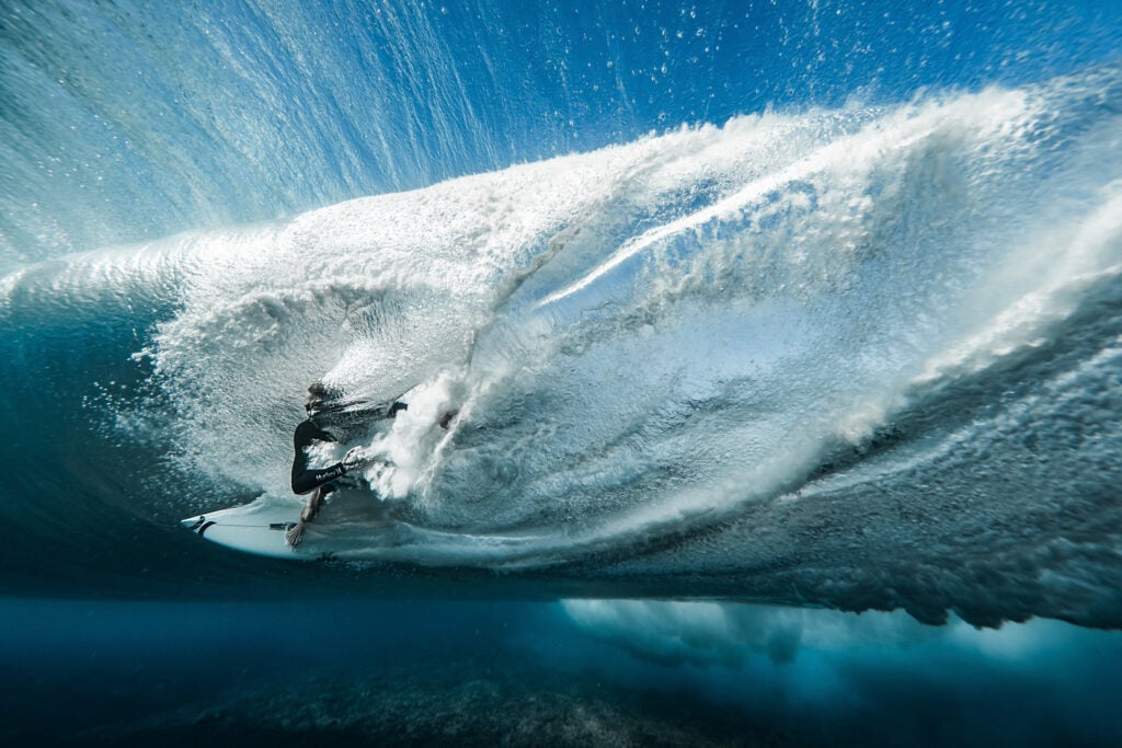 underwater shot of Ace Buchan kicking out from the barrel through the wave