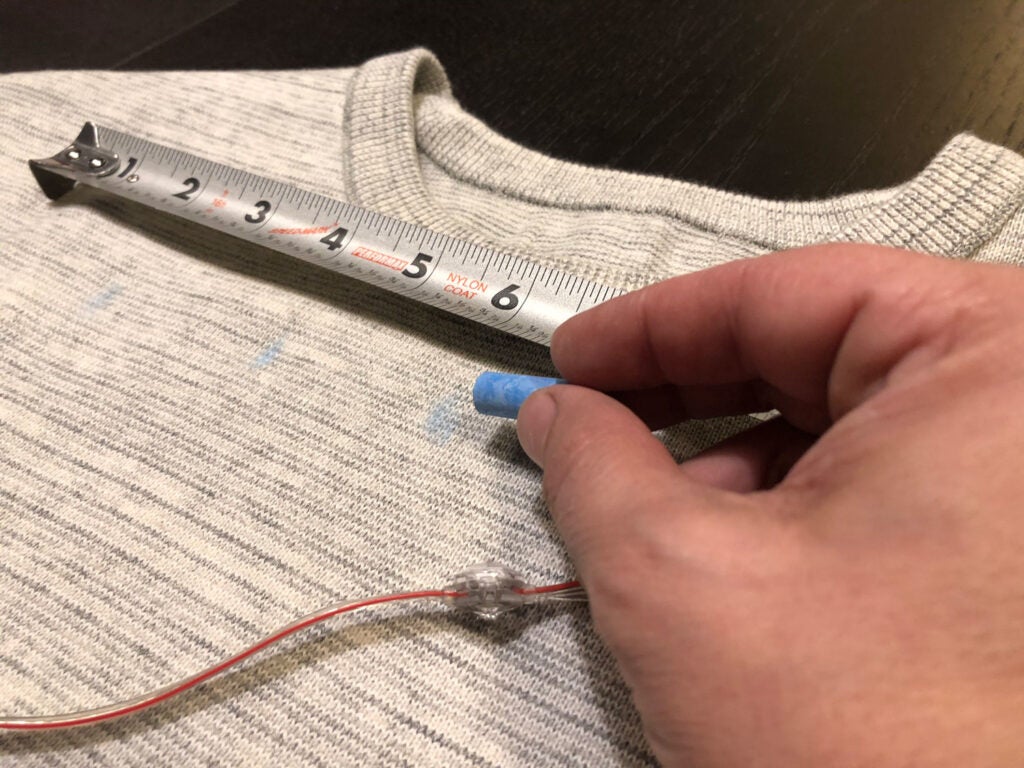 a person drawing a grid on a sweater with tailor's chalk