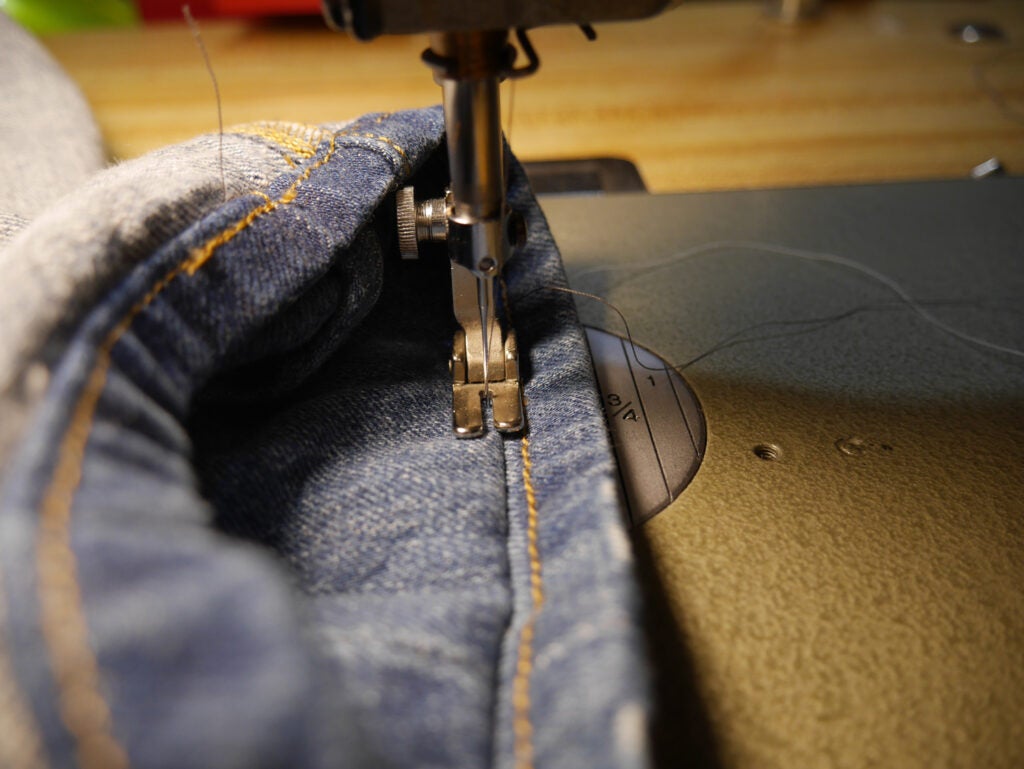 a sewing machine stitching jeans in the Hollywood Hem style