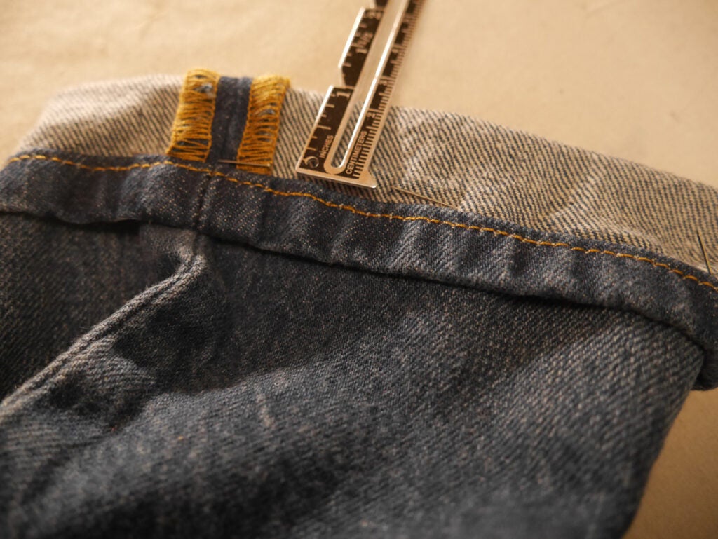 a photo of jeans being hemmed in the Hollywood Hem style, with a ruler