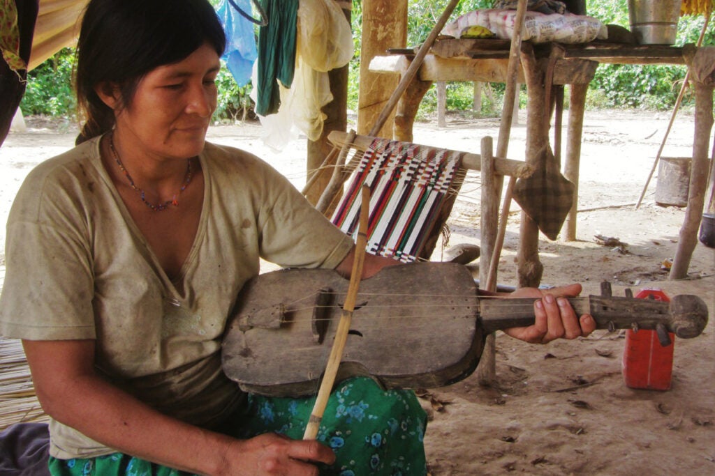 A Tsimane’ woman in Bolivian Amazonia playing a handmade wooden violin