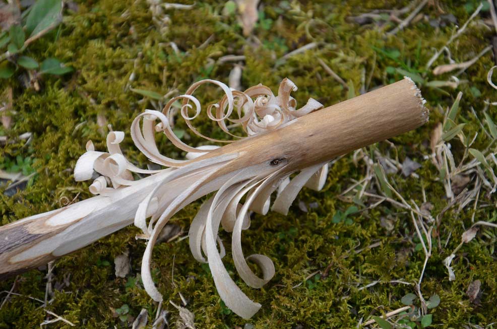 A feathered wood-carved stick for fire-starting.