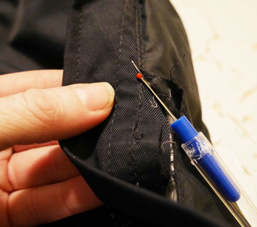 a person ripping seams out of a jacket with a seam ripper to replace a zipper