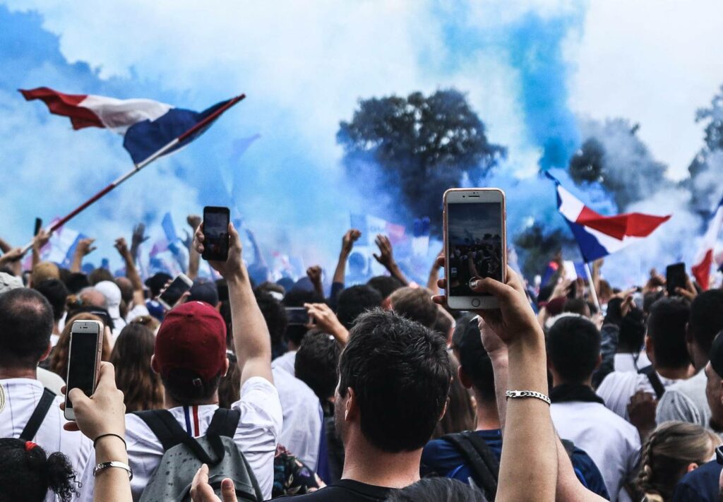 A person using a smartphone to film or livestream a protest on a sunny day in France.