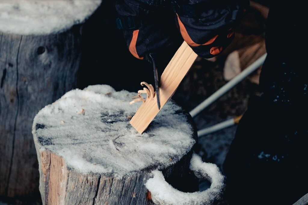 a person carving wood on a log covered in snow