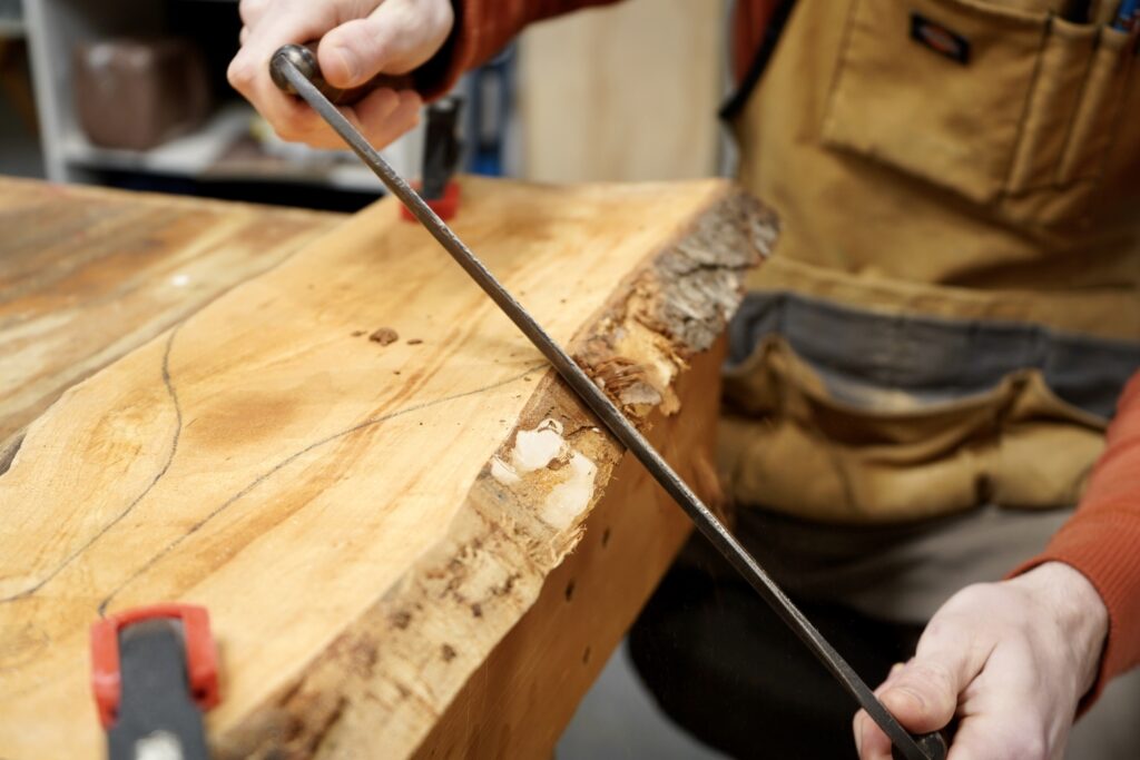 a person removing bark from a live edge piece of cherry wood, for a homemade cutting board