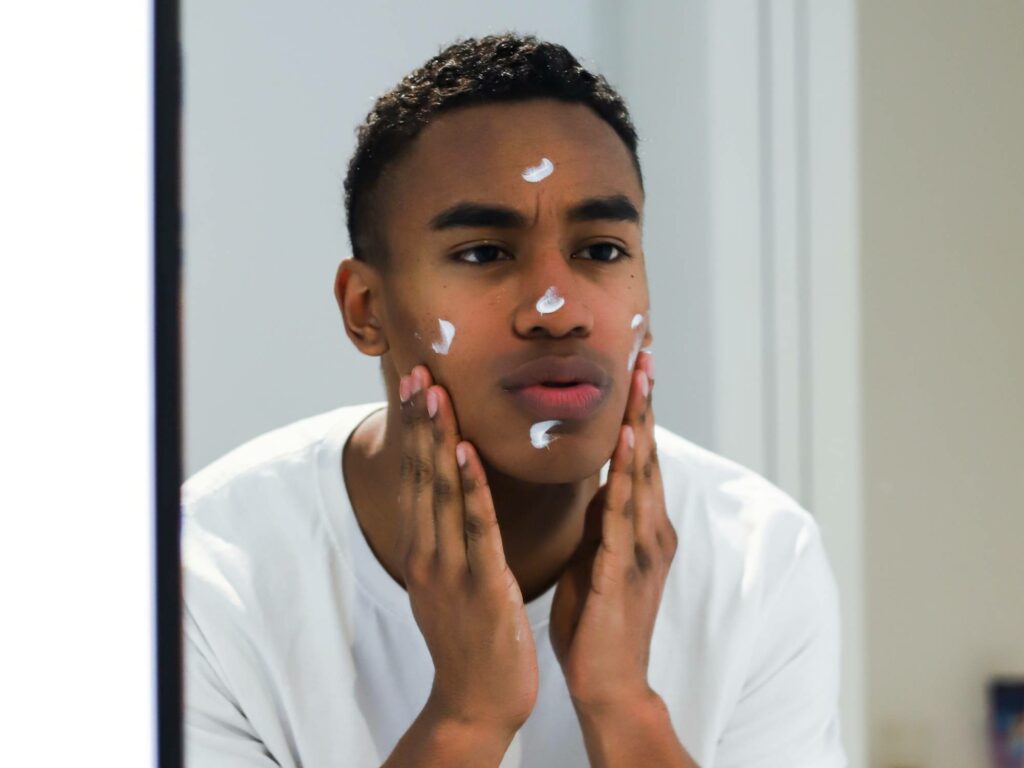 Person applying lotion in mirror