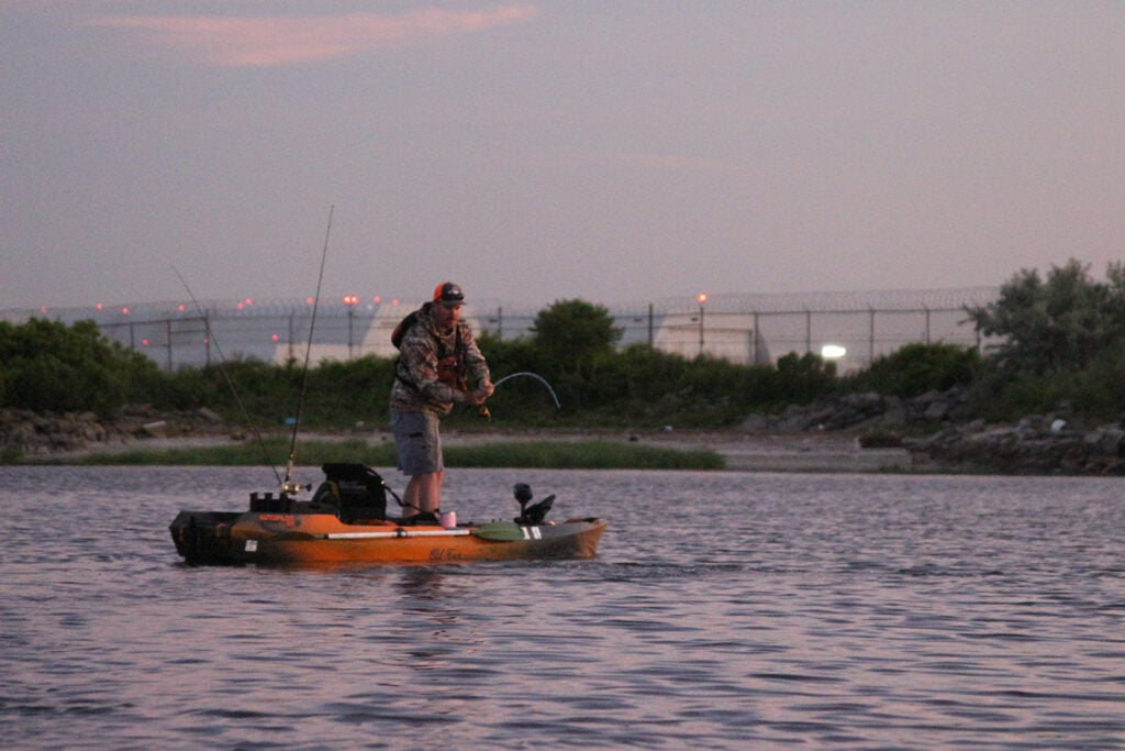 A person fishing off the back of a fishing kayak.