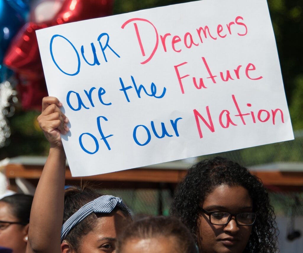 A DACA supporter holds up a sign saying, 