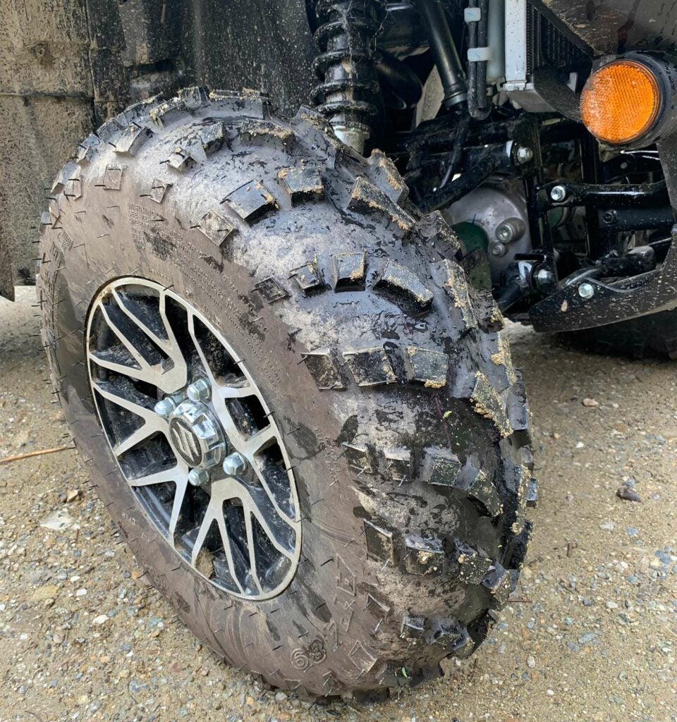 The wet and muddy tires of a Suzuki ATV four-wheeler.