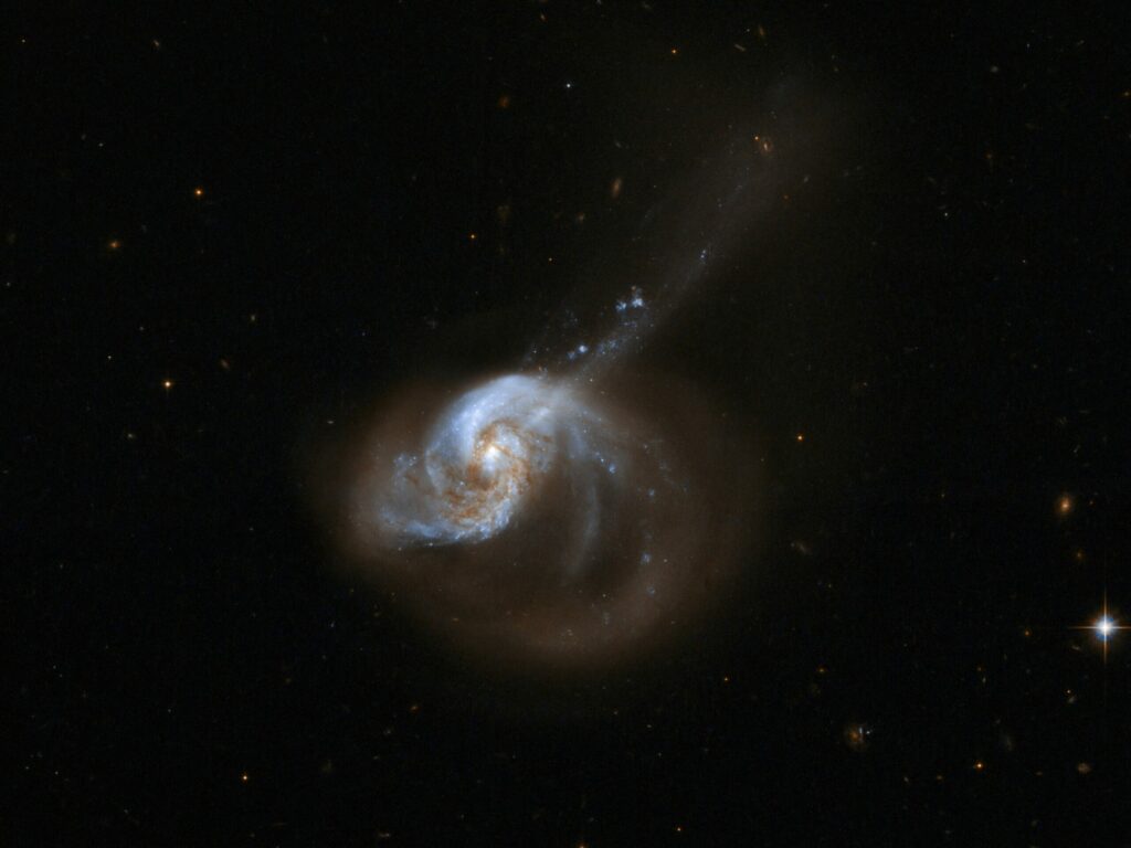 The galaxy system NGC 1614 has a bright optical centre and two clear inner spiral arms that are fairly symmetrical. It also has a spectacular outer structure that consists principally of a large one-sided curved extension of one of these arms to the lower right, and a long, almost straight tail that emerges from the nucleus and crosses the extended arm to the upper right. The galaxy appears to be the result of a tidal interaction and the resulting merger of two predecessor systems. The system has a nuclear region of quasar-like luminosity, but shows no direct evidence for an active nucleus. It is heavily and unevenly reddened across its nucleus, while infrared imaging also shows a 