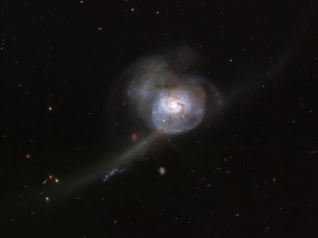 Appearing within the boundless darkness of space, the NASA/ESA Hubble Space Telescope’s snapshot of NGC 34 looks more like an otherworldly, bioluminescent creature from the deep oceans than a galaxy. Lying in the constellation Cetus (The Sea Monster), the galaxy’s outer region appears almost translucent, pinpricked with stars and strange wispy tendrils. The main cause for this galaxy’s odd appearance lies in its past. If we were able to reverse time by a few million years, we would see two beautiful spiral galaxies on a direct collision course. When these galaxies collided into one another, their intricate patterns and spiral arms were permanently disturbed. This image shows the galaxy's bright centre, a result of this merging event that has created a burst of new star formation and lit up the surrounding gas. As the galaxies continue to intertwine and become one, NGC 34’s shape will become more like that of an peculiar galaxy, devoid of any distinct shape.  In the vastness of space, collisions between galaxies are quite rare events, but they can be numerous in mega-clusters containing hundreds or even thousands of galaxies.