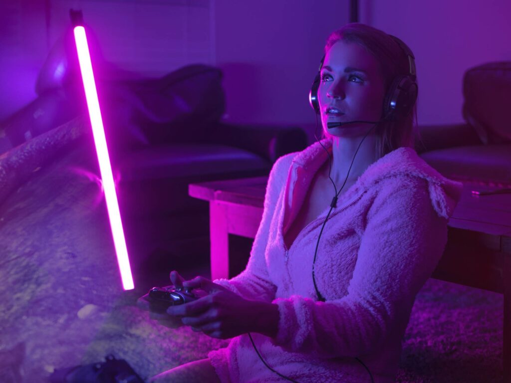 Person playing video games in the dark with a pink neon light