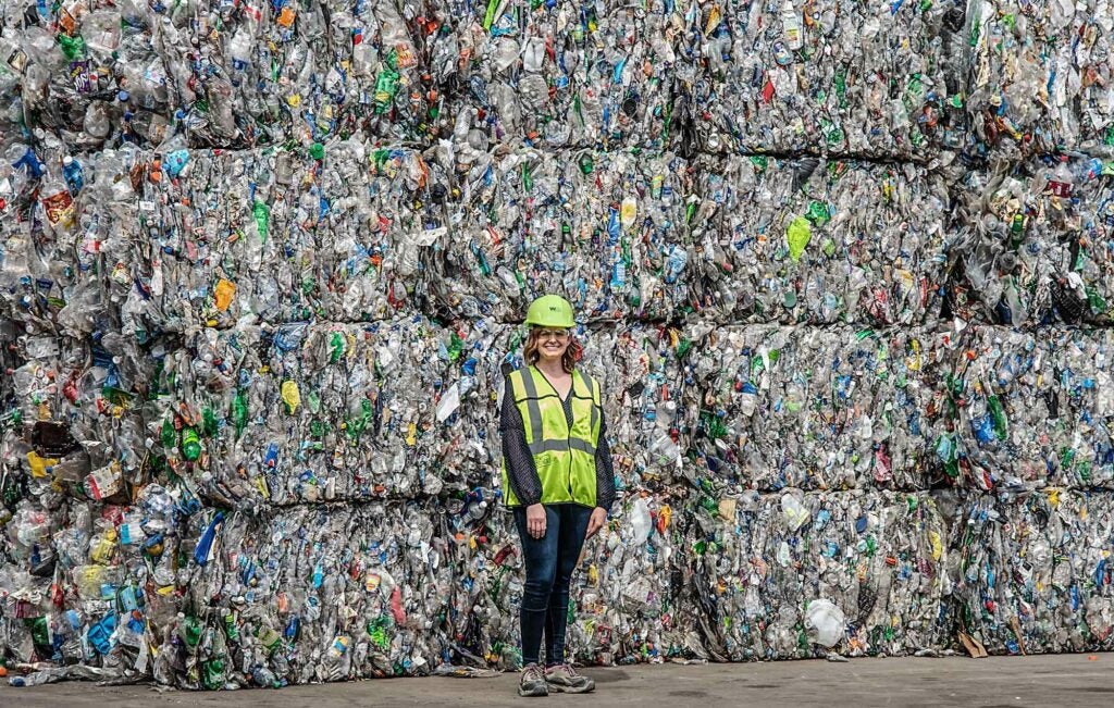 spokesperson for Waste Management stands with bales of plastic garbage