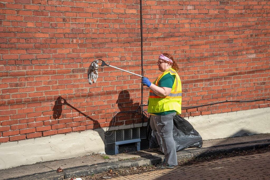 A volunteer in a clean-up crew picks up a piece of discarded plastic